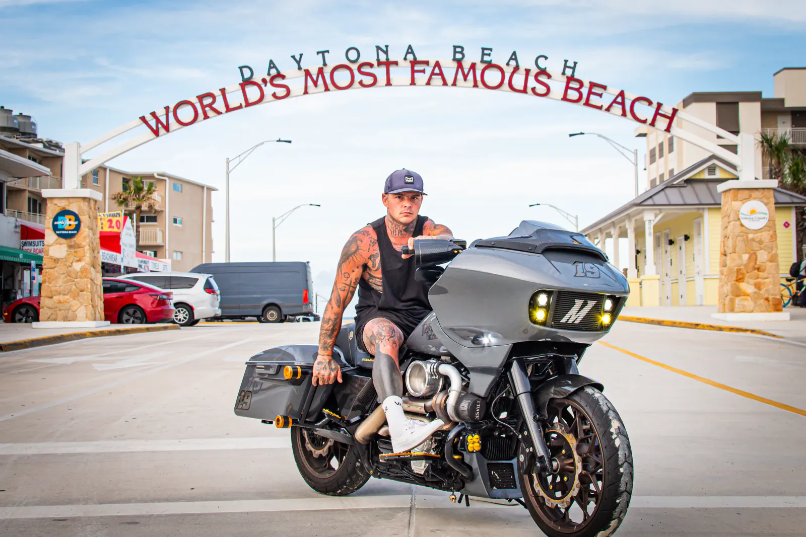 Rider on a custom gray bagger under the Daytona Beach “World's Most Famous Beach” arch